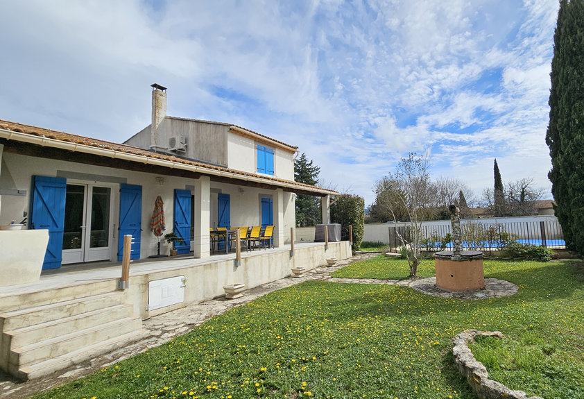 La maison et sa terrasse aux volets bleus, vue depuis le jardin