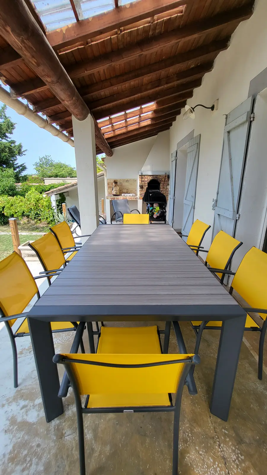 La grande table de la terrasse couverte, dressée pour un repas en famille